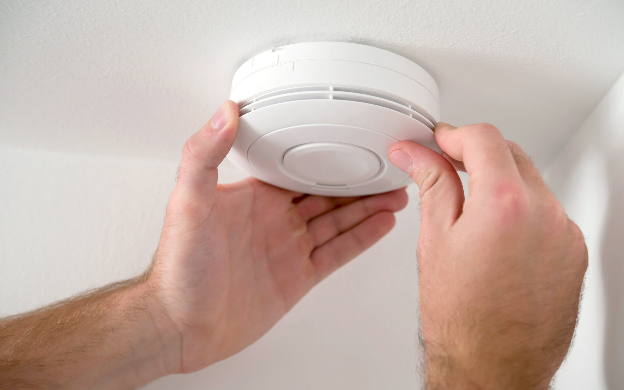 Image of a man's hands changing a smoke alarm