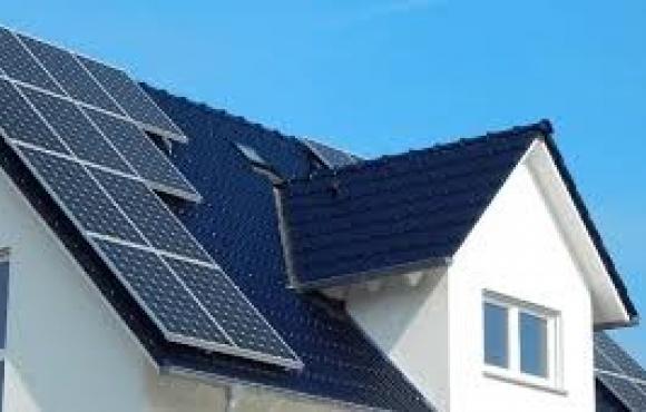 A close up of the roof of a white house with a black roof. There are solar panels on the roof of the house.