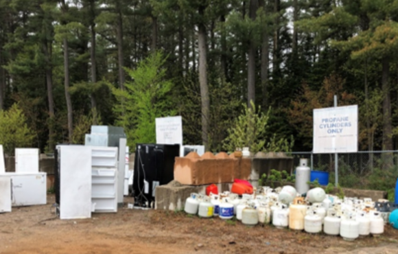 At a landfill site, different materials have been sorted into piles such as gas tanks, plastic bottles, etc.