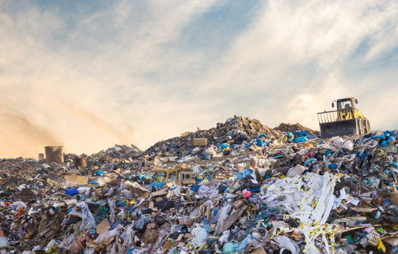 The bottom half of the photo is a landfill hill with garbage piled up, and the top half of the photo shows a cloudy sky