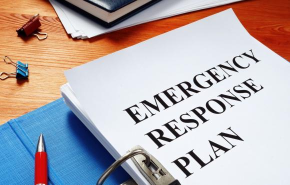 a binder is open to a title page with the words "Emergency response plan" written on a blank white page