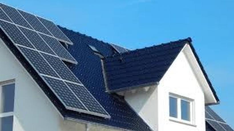 A close up of the roof of a white house with a black roof. There are solar panels on the roof of the house.